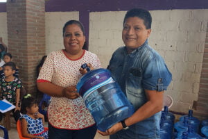 A man and woman hold a water jug of safe water in Mexico