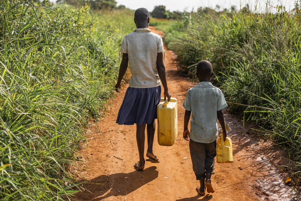 2 children carrying water jugs