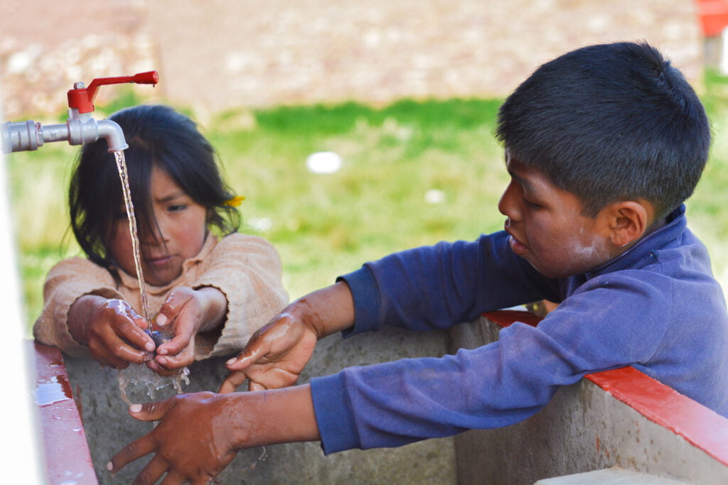 Children using a water spout to wash their hands, they are coping with the mexico water shortage