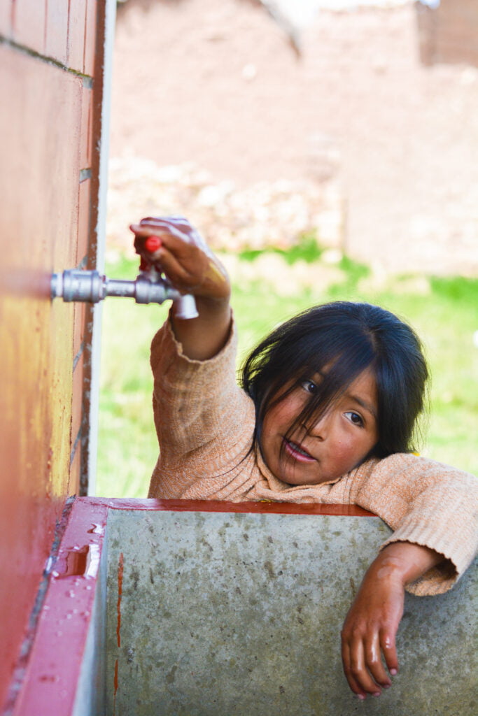 A little girl reaches up to the knob to turn on the water spout, she is suffering from the mexico water crisis