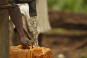 A child's hand can be seen filling a portable water jug in the Sierra Leone Water Crisis